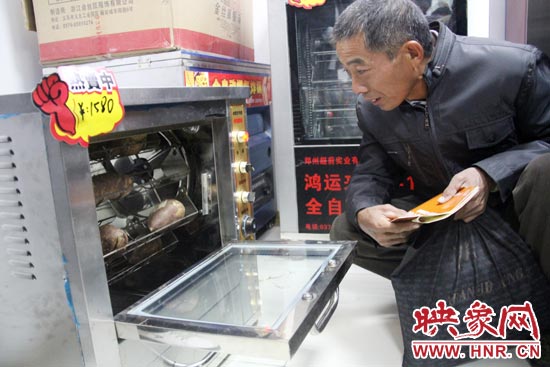 一名科技會員在看一臺自動化烤紅薯機(jī)器 一名科技會員在看一臺自動化烤紅薯機(jī)器