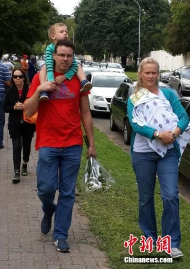 圖為一個(gè)白人家庭，由父母帶著孩子到曼德拉家門外悼念。中新社發(fā) 宋方燦 攝