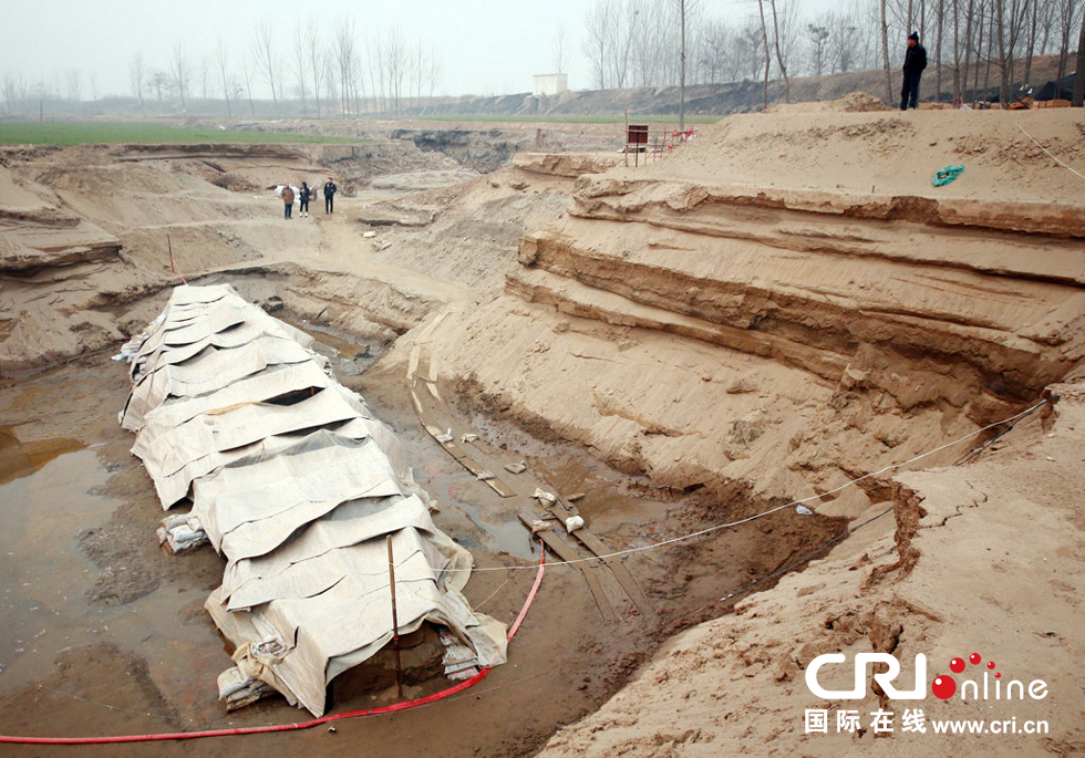2014年1月6日，河南洛陽古沉船發(fā)掘現(xiàn)場，近日有雨雪天，考古人員給古沉船披上一層“雨衣”。