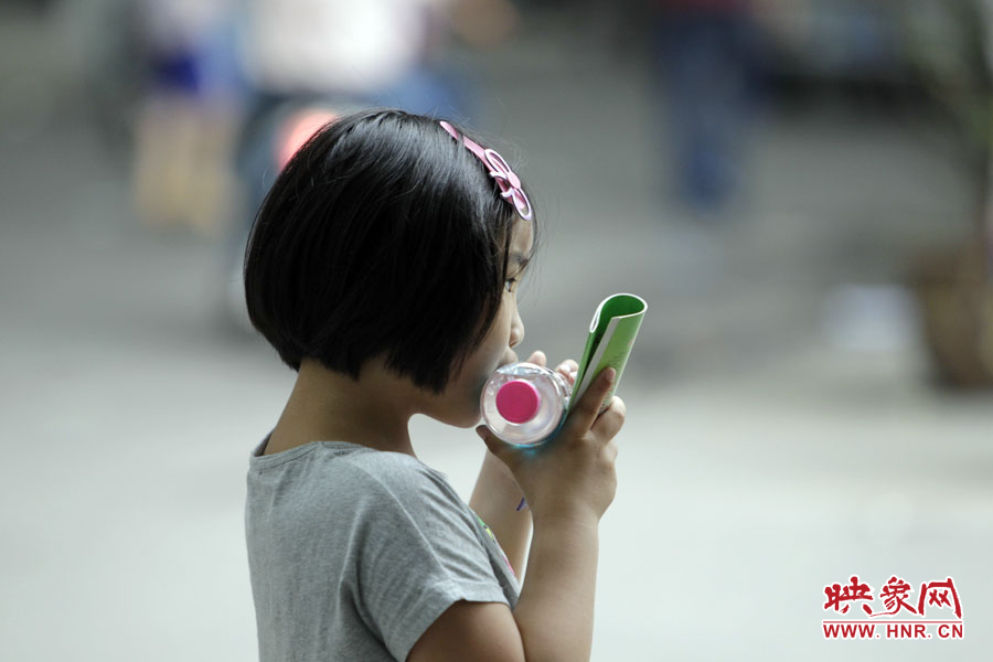 6月7日，鄭州回中考點，一名孩子拿著一瓶礦泉水，等待哥哥走出考場