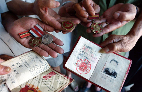 幾位志愿軍老兵展示自己的立功證、傷殘軍人證與勛章