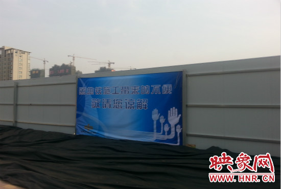 道路南側(cè)圍起了白色的圍擋，墻上標(biāo)示著“因地鐵施工帶來的不便敬請(qǐng)您諒解”的提示牌。