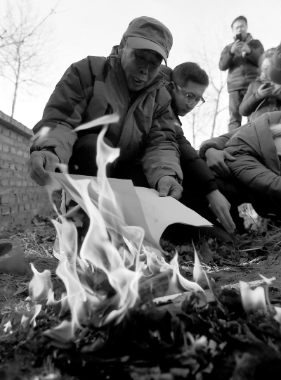 李三仁在兒子墳前焚燒再審無(wú)罪判決文書(shū)的復(fù)印件。新華社發(fā)