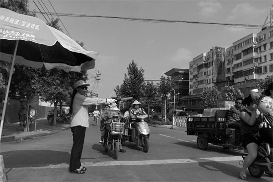 昨日，開(kāi)封市區(qū)一名協(xié)管員在指揮群眾過(guò)馬路