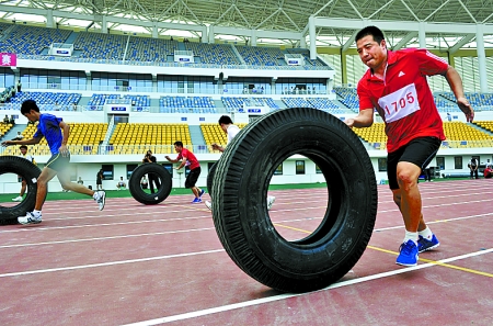 8月15日，運(yùn)動員們正在進(jìn)行推輪胎賽跑。