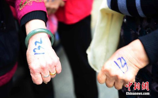 圖為10月28日，在江西九江市一家羊絨皮草服裝服飾博覽會現(xiàn)場，老人們正在頂著寒風排隊等待領(lǐng)取10元代金劵。